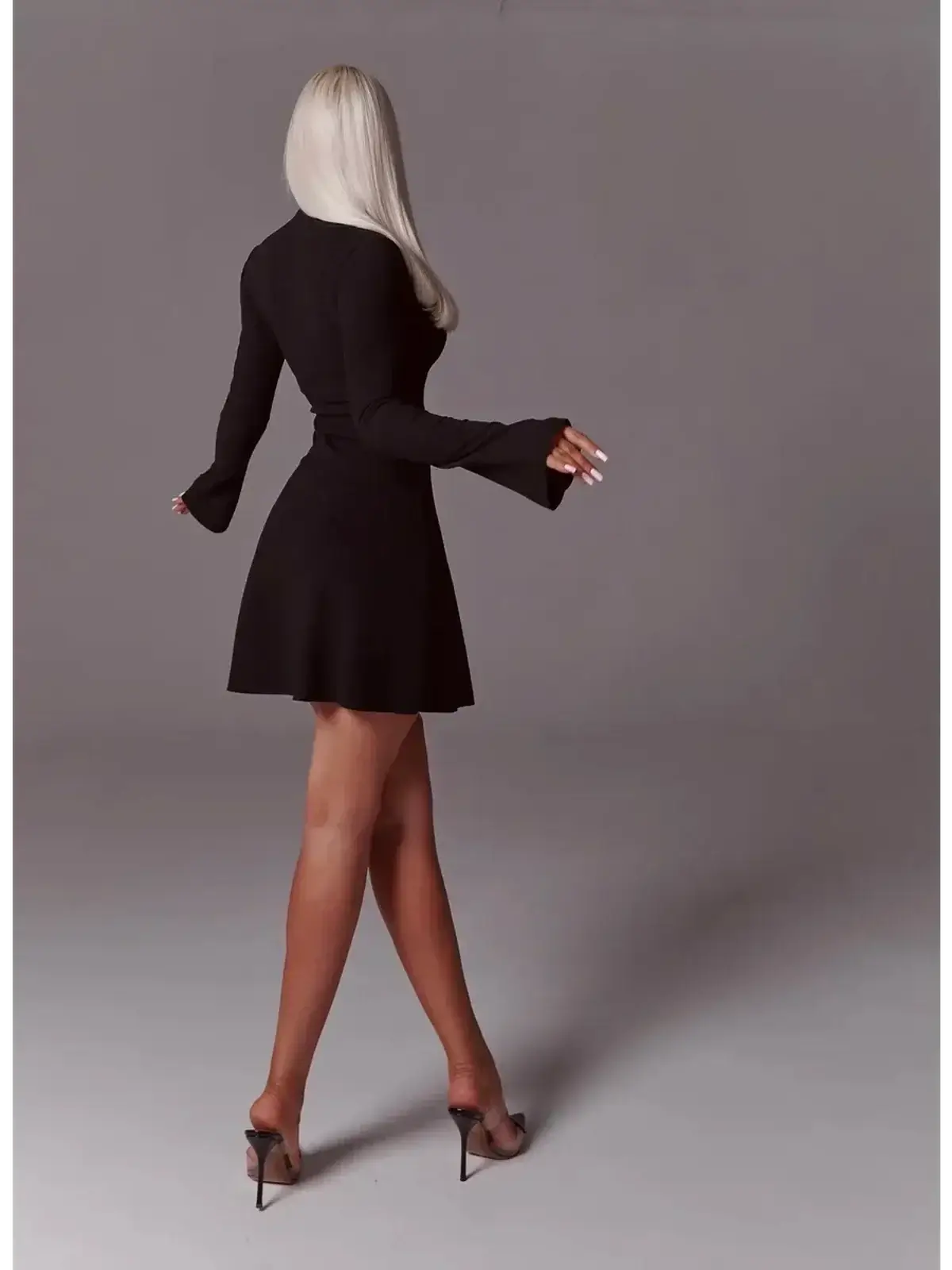 Back view of a woman in a black mini dress with flared sleeves, showcasing a chic and elegant look.