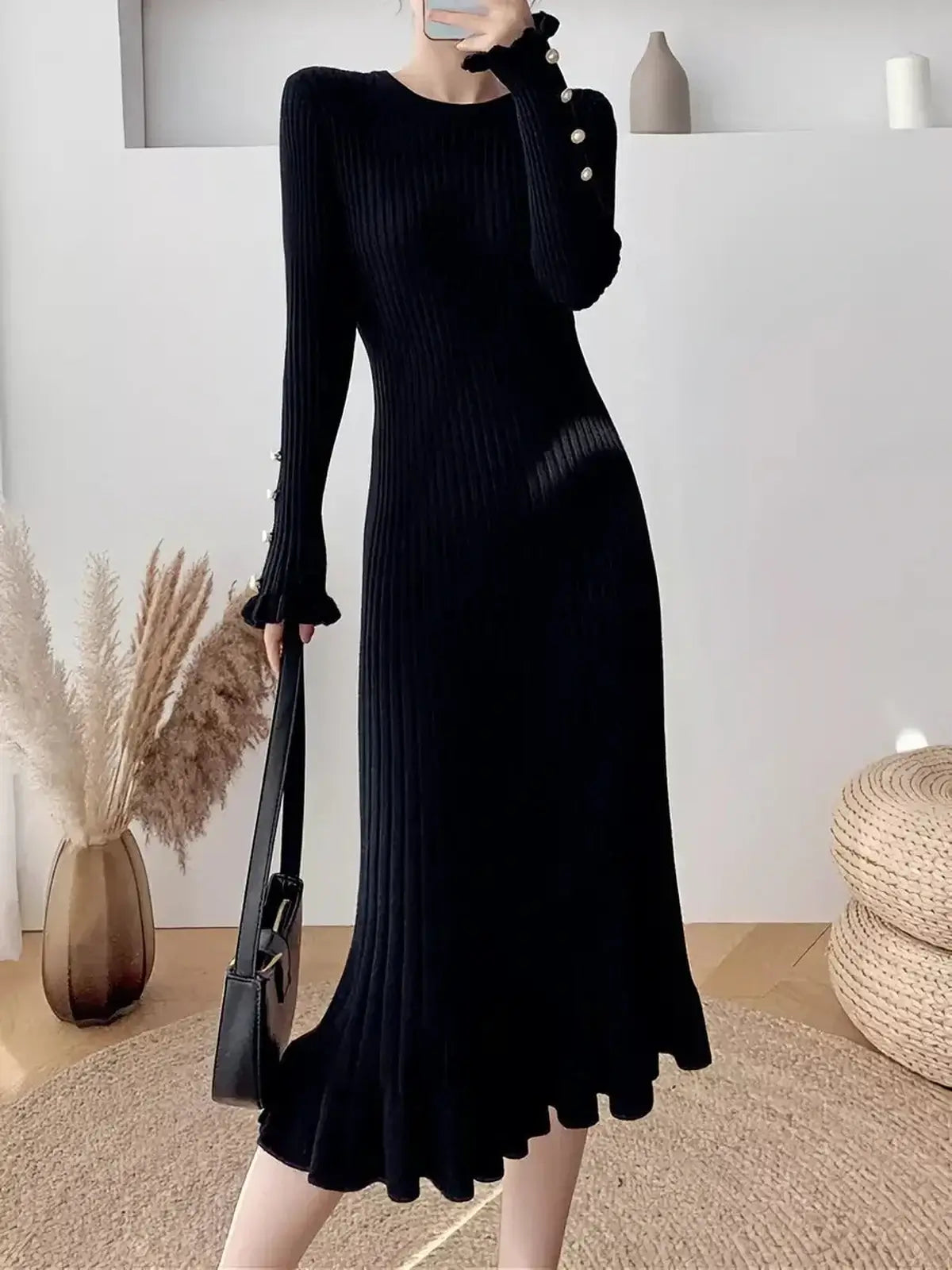 Sculpted Pearl Midi Dress in black, featuring ribbed knit fabric, flared cuffs with pearl buttons, and a feminine ruffled hem.