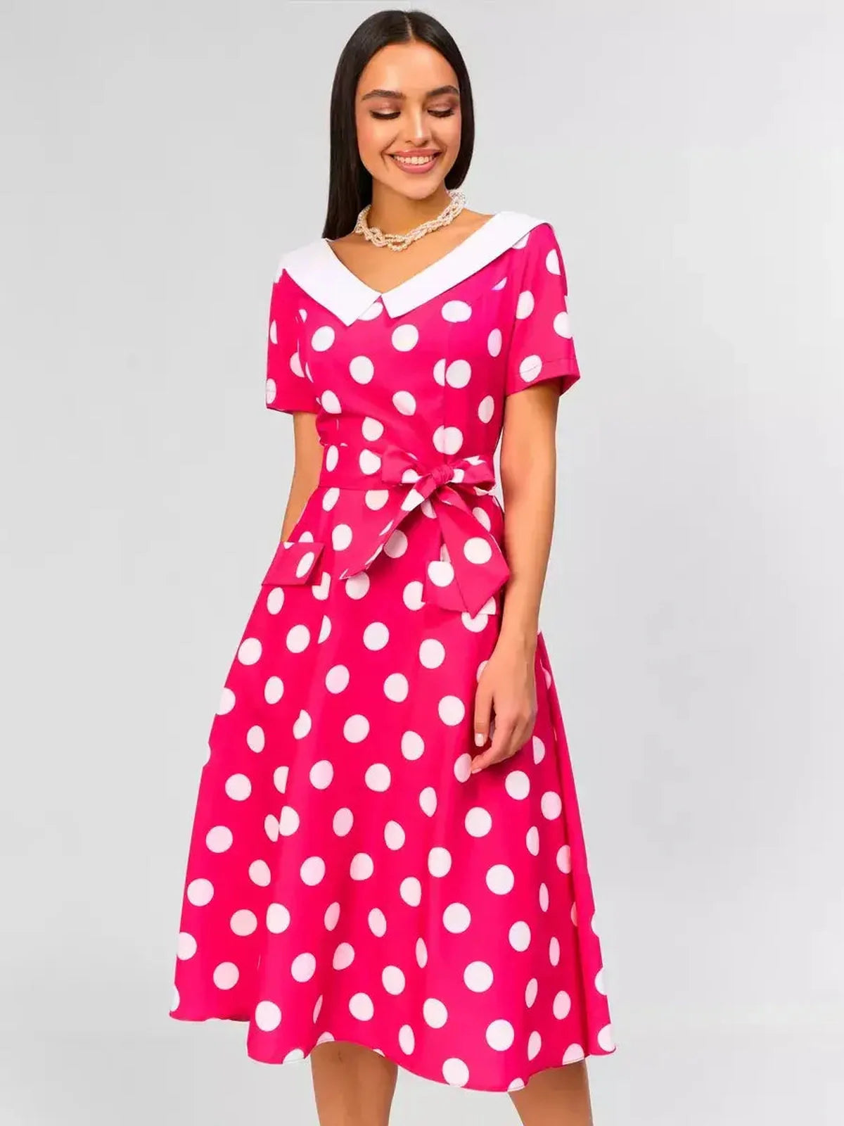 Stylish pink polka dot midi dress with a white collar and tie waist, perfect for weddings and summer occasions.