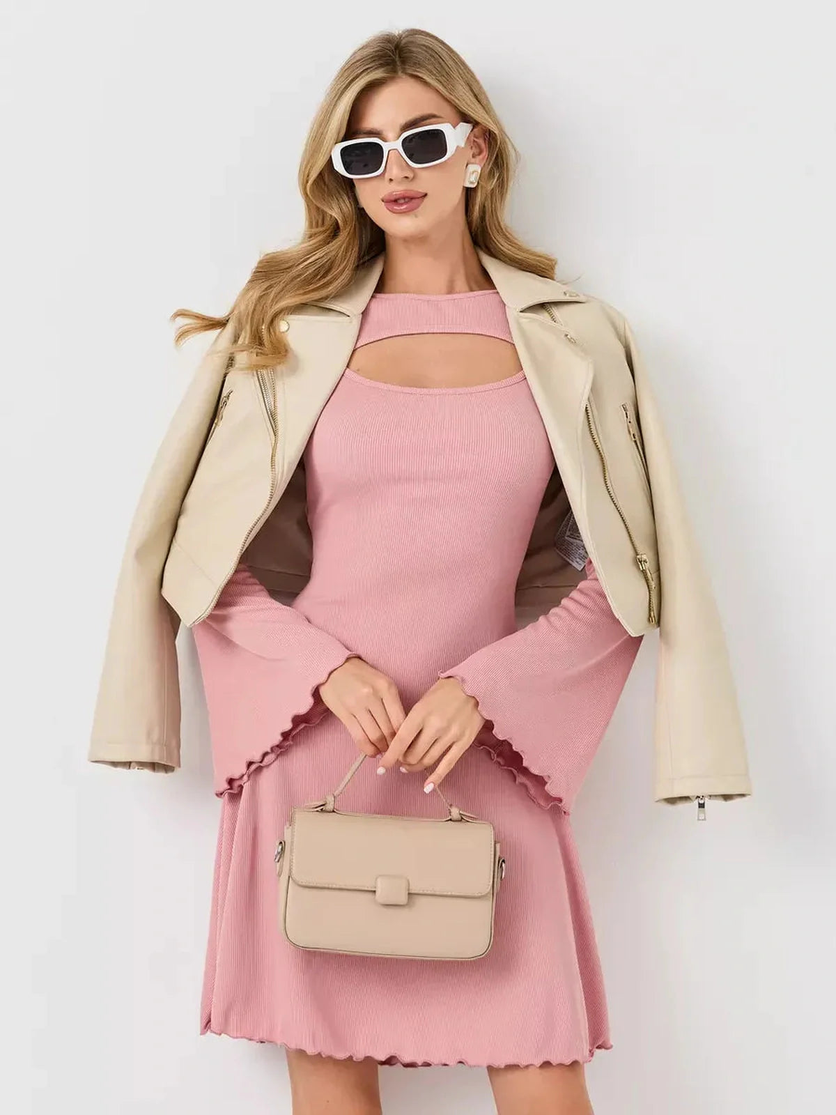 Stylish woman in a pink dress with flared sleeves, wearing sunglasses and a beige jacket, perfect for summer occasions.