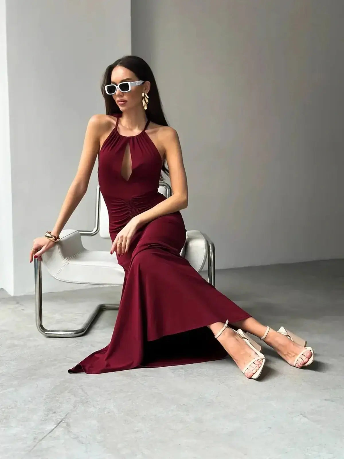 Model in a burgundy maxi dress with a halter neck and keyhole detail, showcasing elegant summer or formal style.