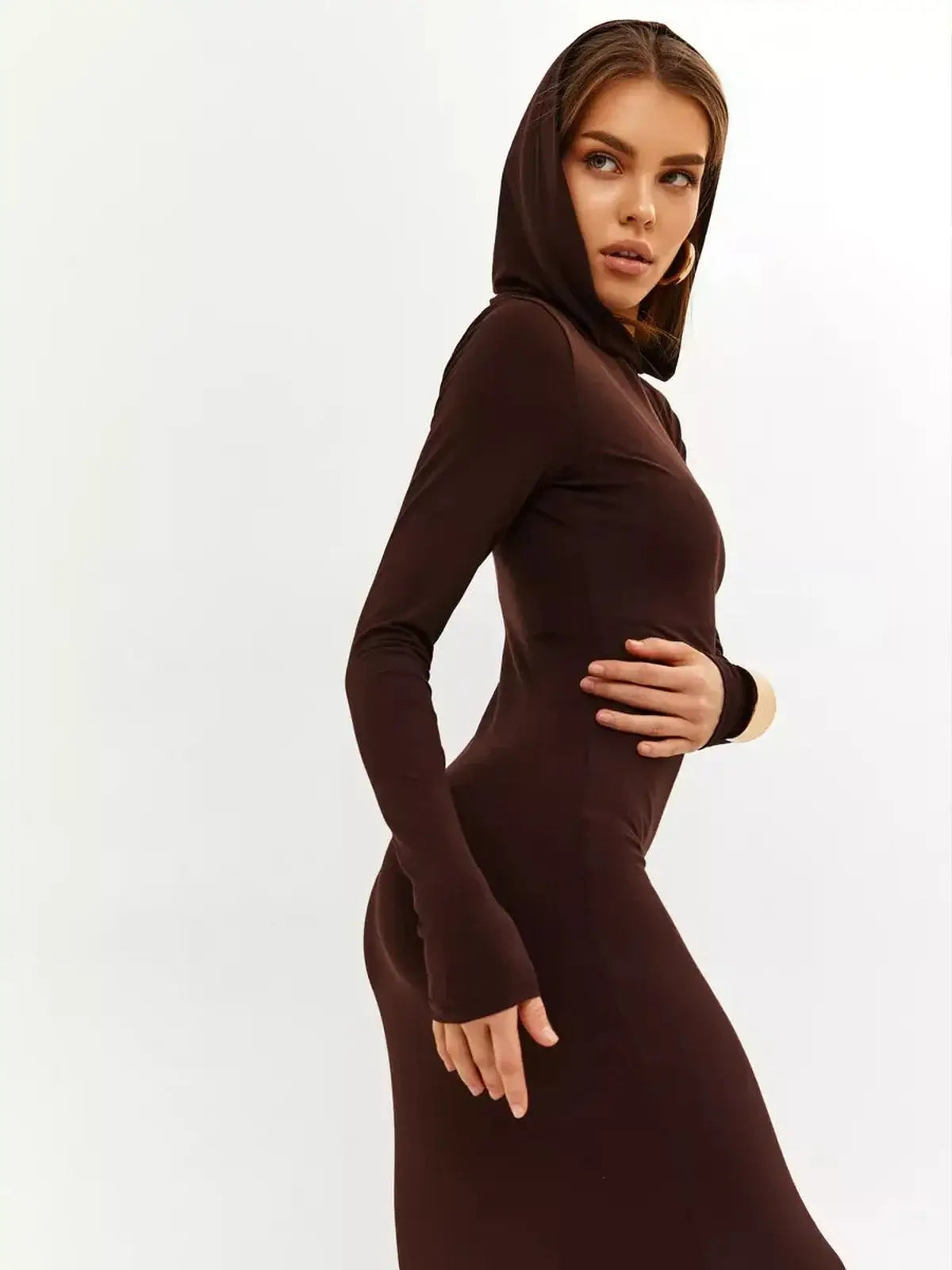 Model showcasing the Sculpt Maxi Dress in rich chocolate, featuring a hood and sleek silhouette for modern elegance.