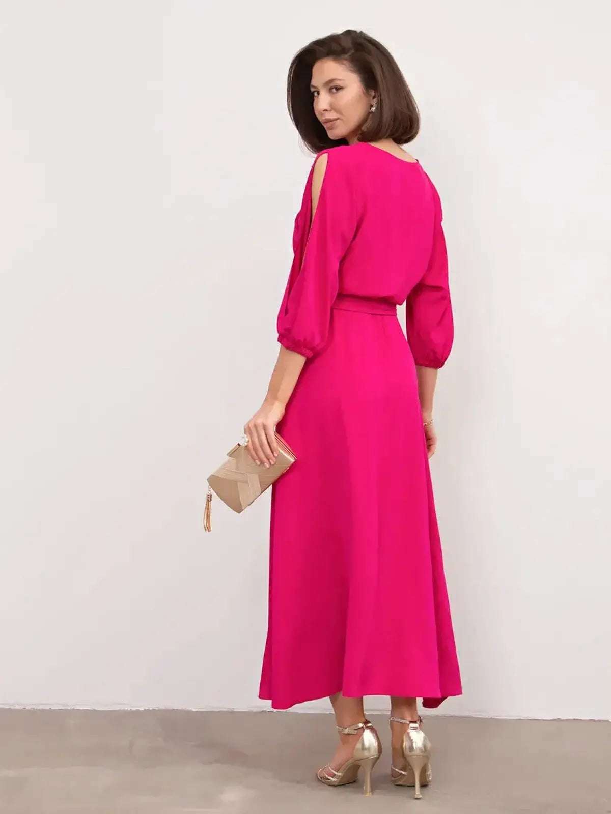 Stylish woman in a fuchsia Twilight Bloom Midi Dress with shoulder cutouts and a flowing high-low hemline.