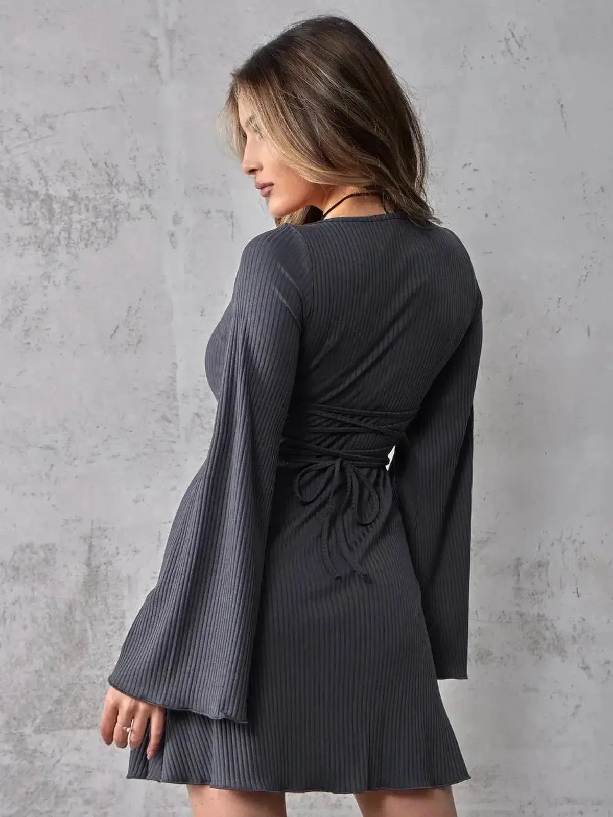 Noir Flare Midi Dress featuring long bell sleeves and a fitted waist, showcasing a chic back view on a textured background.