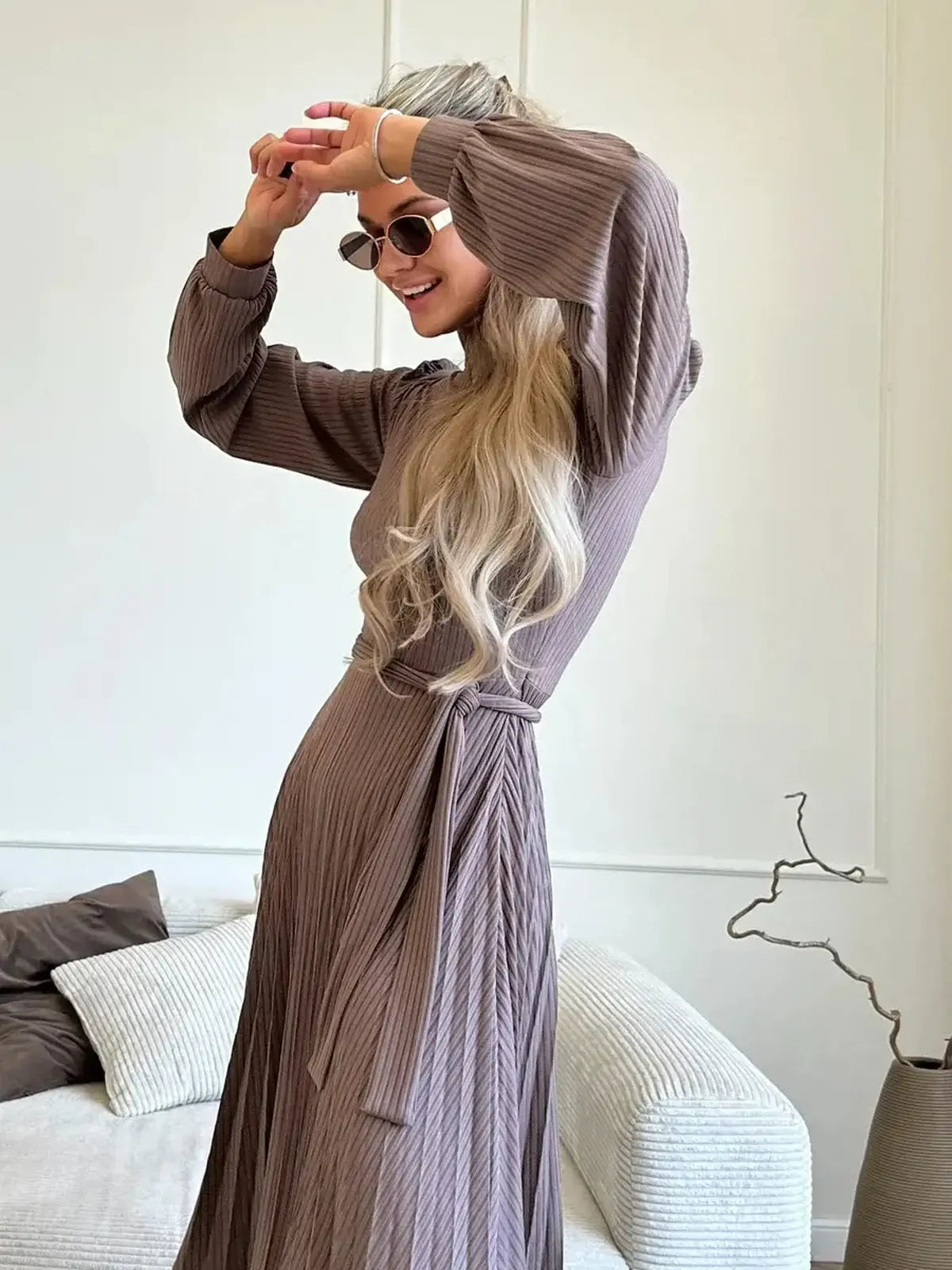 Woman in a ribbed Plissé Charm Midi Dress, posing joyfully with sunglasses, showcasing elegant style and fit.