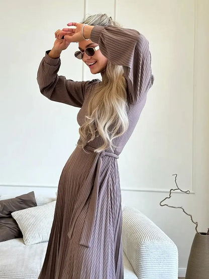 Woman in a ribbed Plissé Charm Midi Dress, posing joyfully with sunglasses, showcasing elegant style and fit.