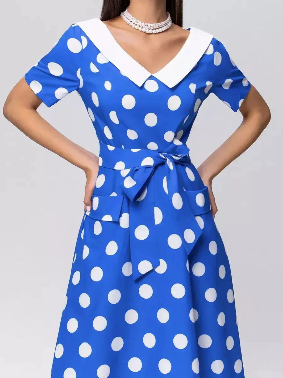 Vibrant azure blue midi dress with white polka dots, V-neckline, and tie belt, perfect for summer occasions.