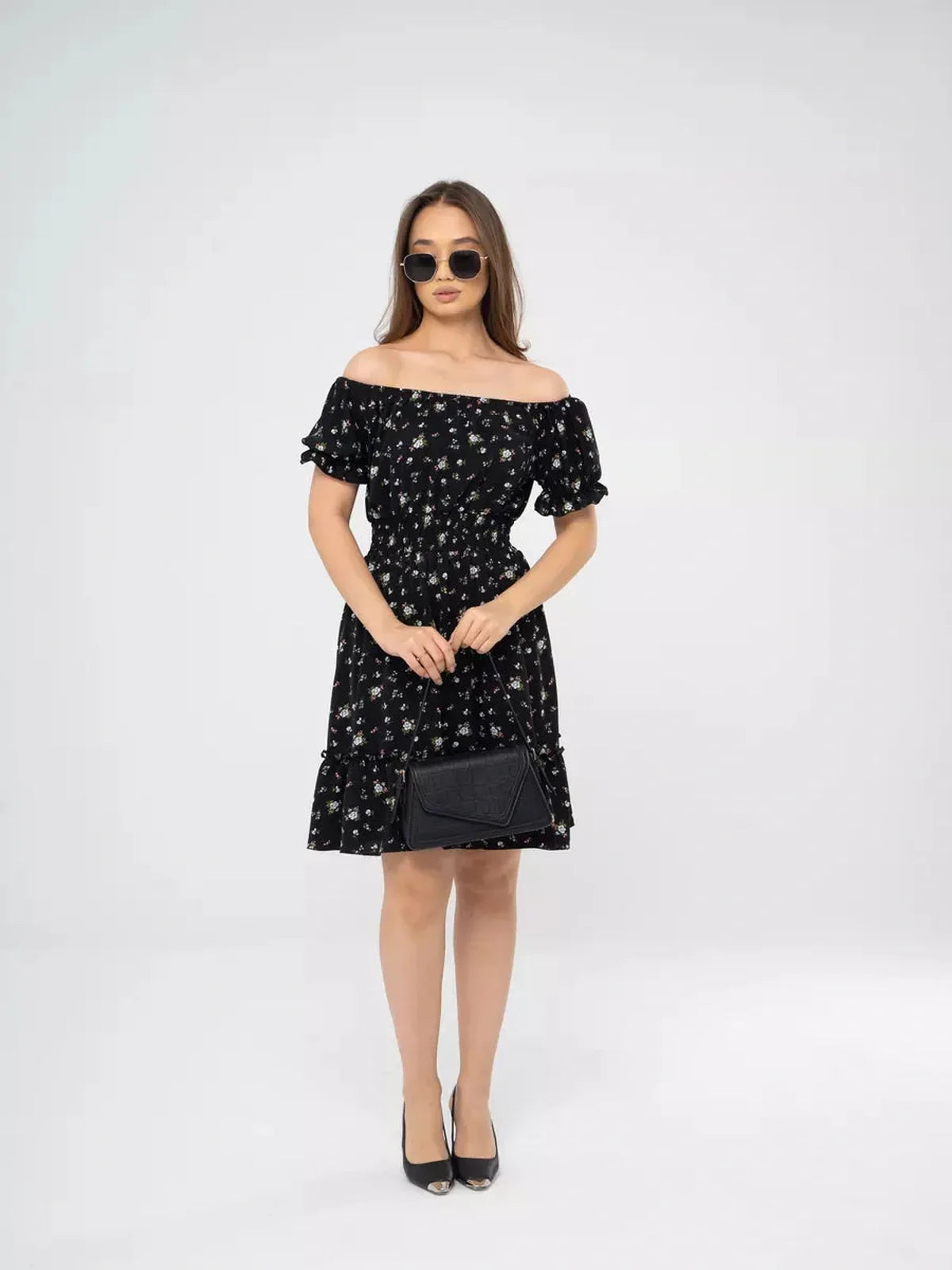 Model wearing a black off-shoulder floral dress, perfect for summer weddings or casual outings.