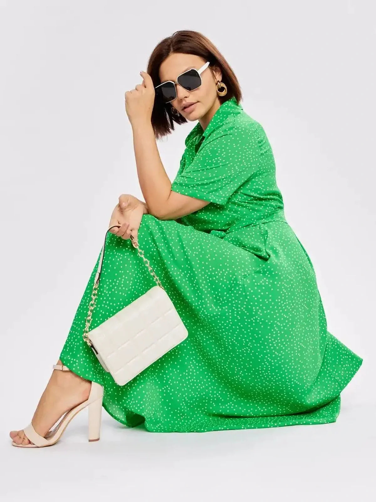 Woman in a green Garden Dot Midi Dress with white dots, styled with sunglasses and a clutch, perfect for summer gatherings.