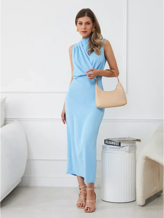 Sculpted Grace Maxi Dress in light blue with draped silhouette, styled for a chic evening look with handbag and heels.