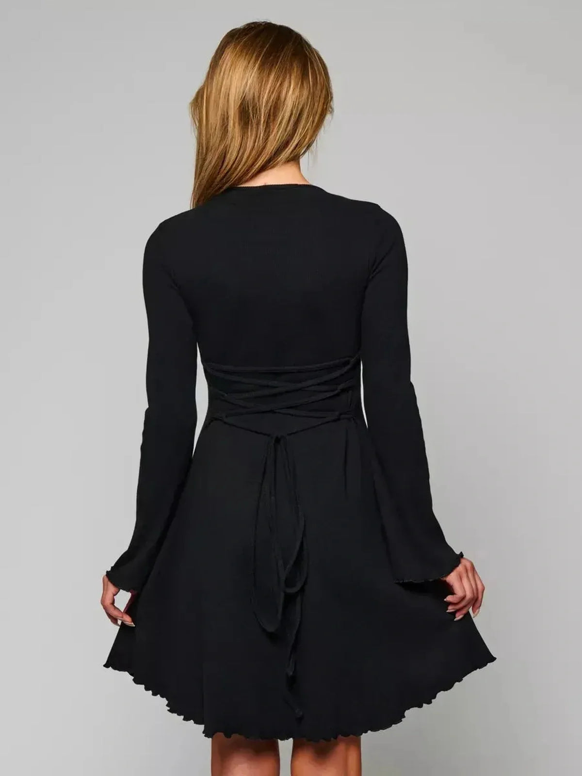Back view of the Velvet Eclipse black mini dress featuring a fitted bodice, flared hem, and elegant bell sleeves.