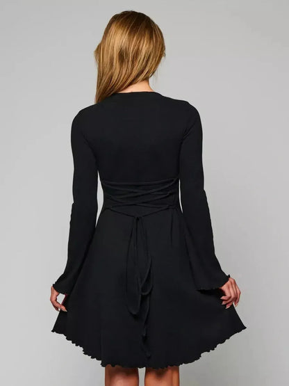 Back view of the Velvet Eclipse black mini dress featuring a fitted bodice, flared hem, and elegant bell sleeves.