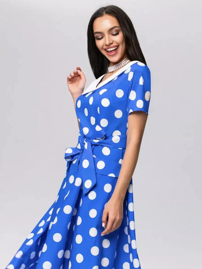 Woman smiling in Midi Dress Azure Dots, featuring a V-neckline, white polka dots, and a stylish tie belt.