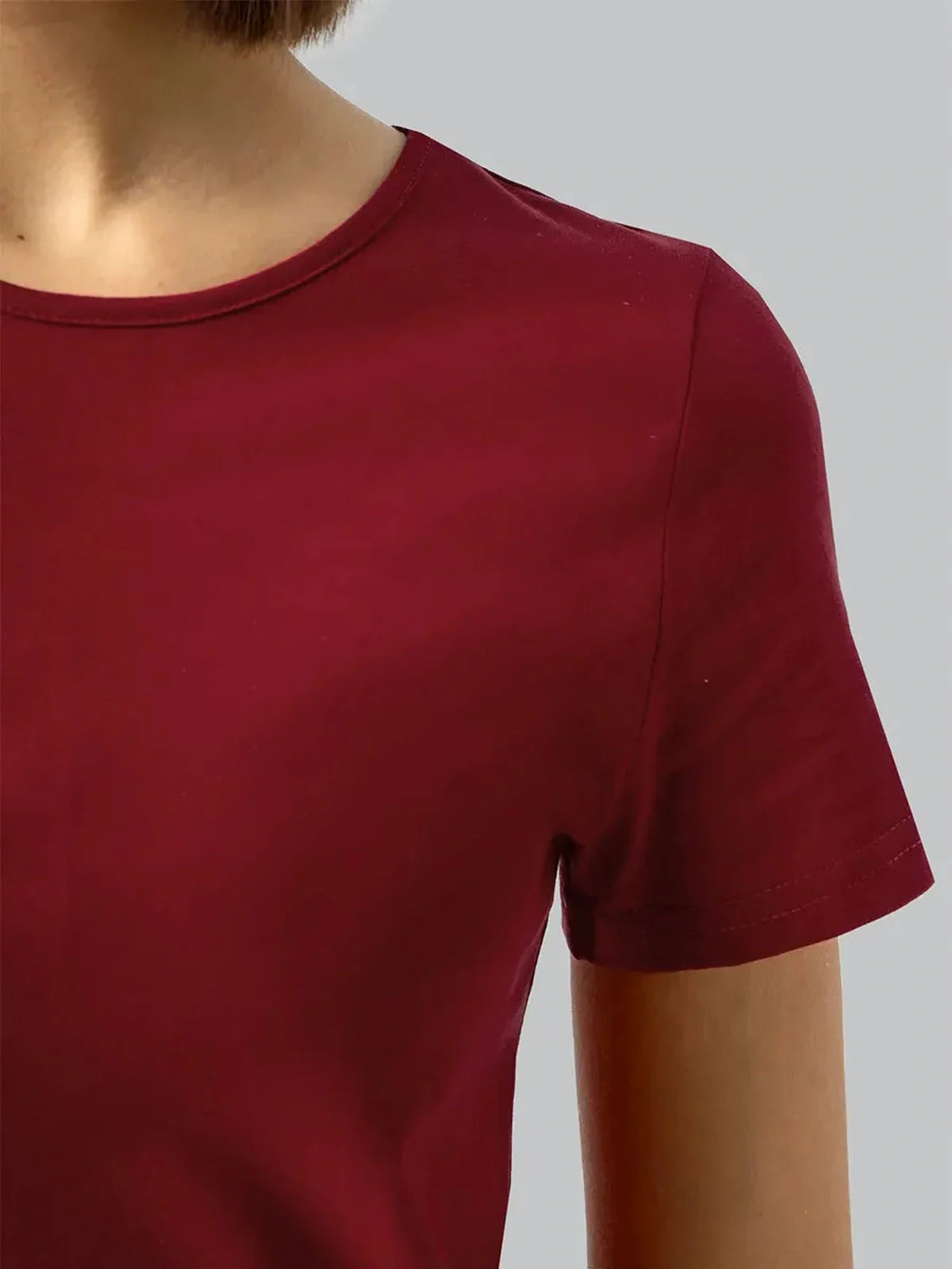 Close-up of a woman wearing a burgundy midi dress featuring a minimalist design and short sleeves.