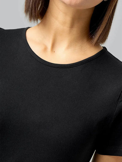 Close-up of a woman's neck and shoulders in a black essential midi dress, showcasing its sleek design and breathable fabric.