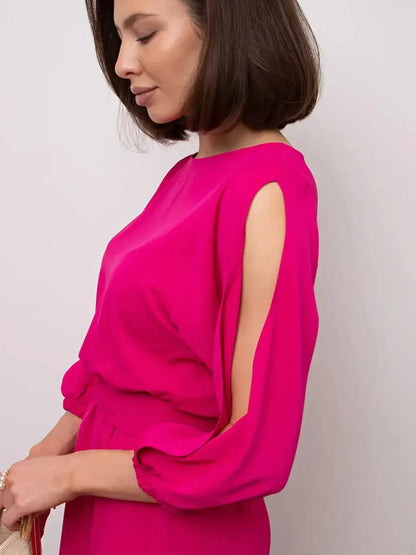 Side view of a woman in a vibrant fuchsia midi dress with shoulder cutouts, showcasing elegance and style.