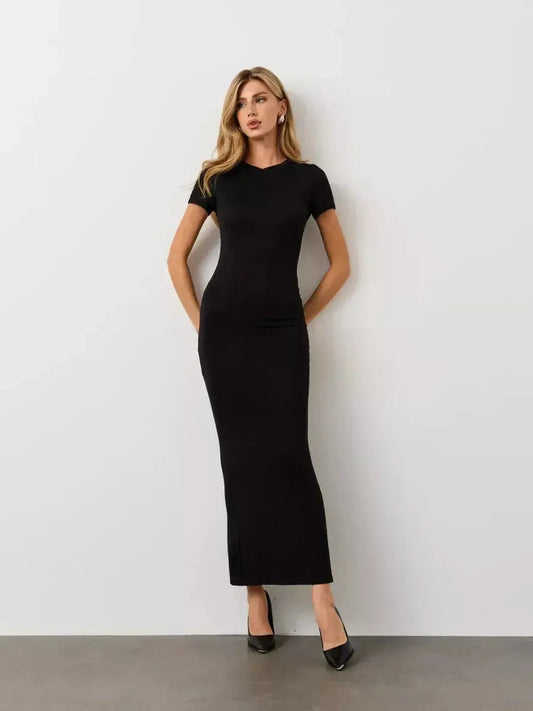 Model in a sleek Noir Curve Maxi Dress features a sculpted silhouette and flared hem, perfect for elegant occasions.