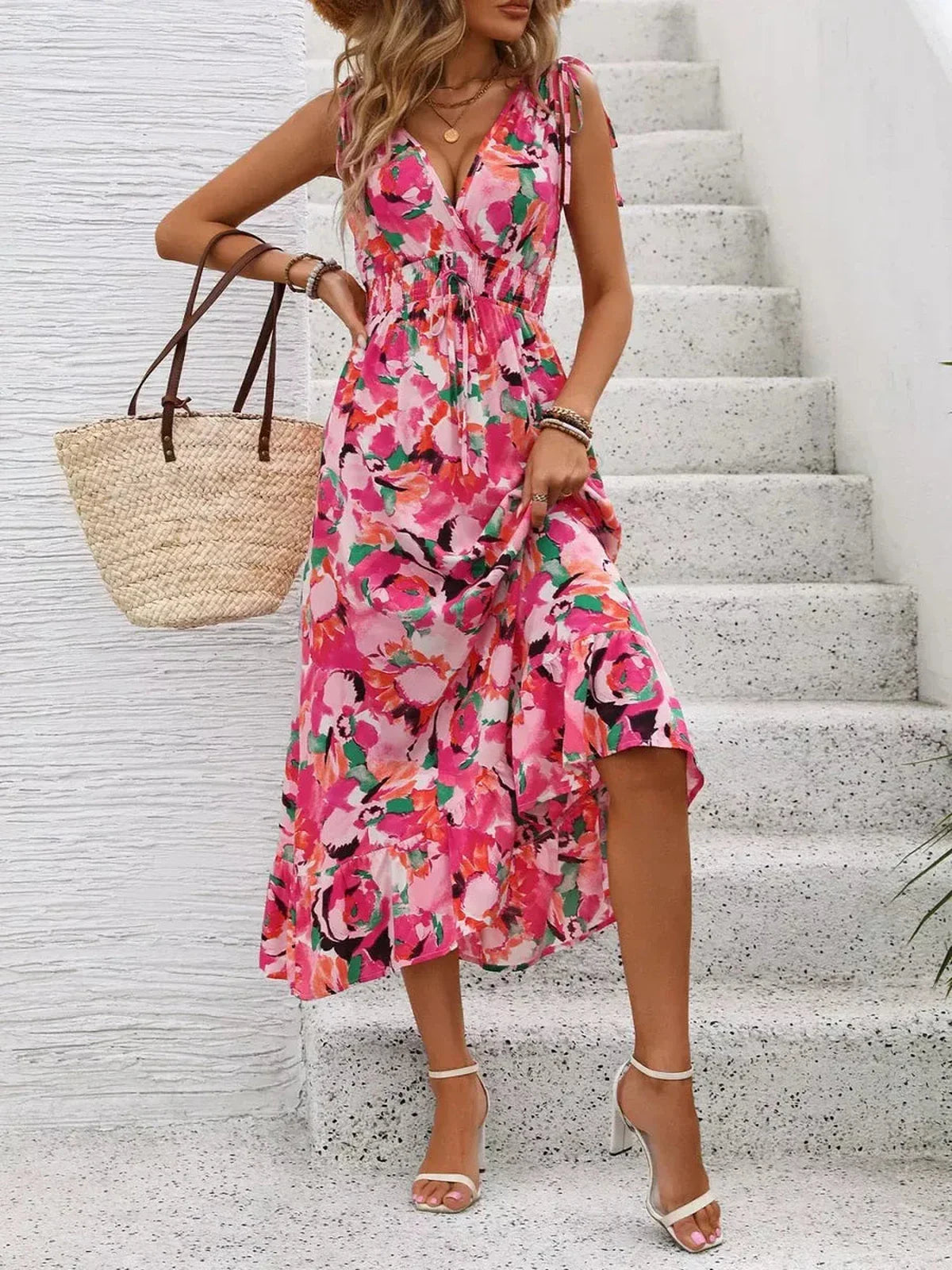 Model in a vibrant pink floral midi dress with tie straps, showcasing summer style and elegance.