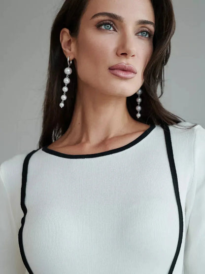Close-up of a model wearing the Framed Elegance Midi Dress with black piping, showcasing sophisticated style and pearl earrings.