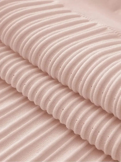 Close-up of luxurious ribbed knit fabric in soft blush color, showcasing texture for elegant dresses.