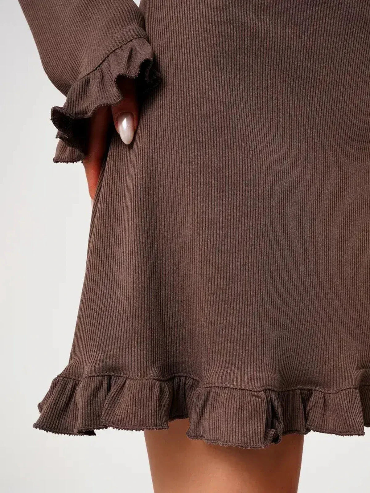 Close-up of the ruffled hem and cuffs of a Mocha Flare ribbed knit mini dress, showcasing its soft fabric and flirty design.