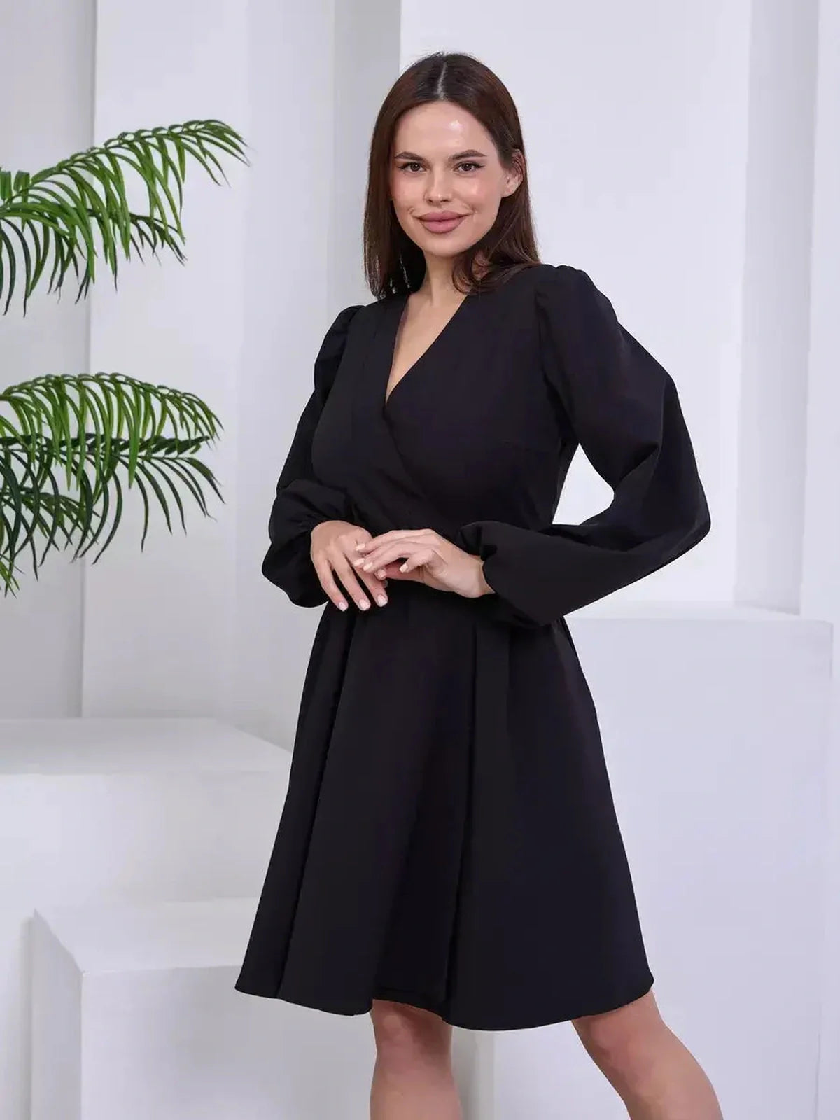 Elegant black mini dress with wrap silhouette and long sleeves, perfect for weddings and cocktail events.