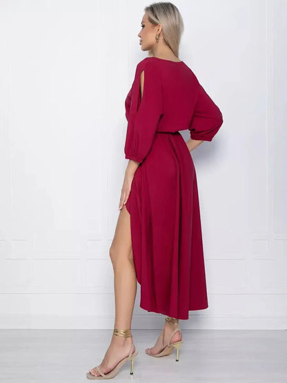 Elegant crimson midi dress featuring a high-low hem and dramatic slit, perfect for weddings and special occasions.