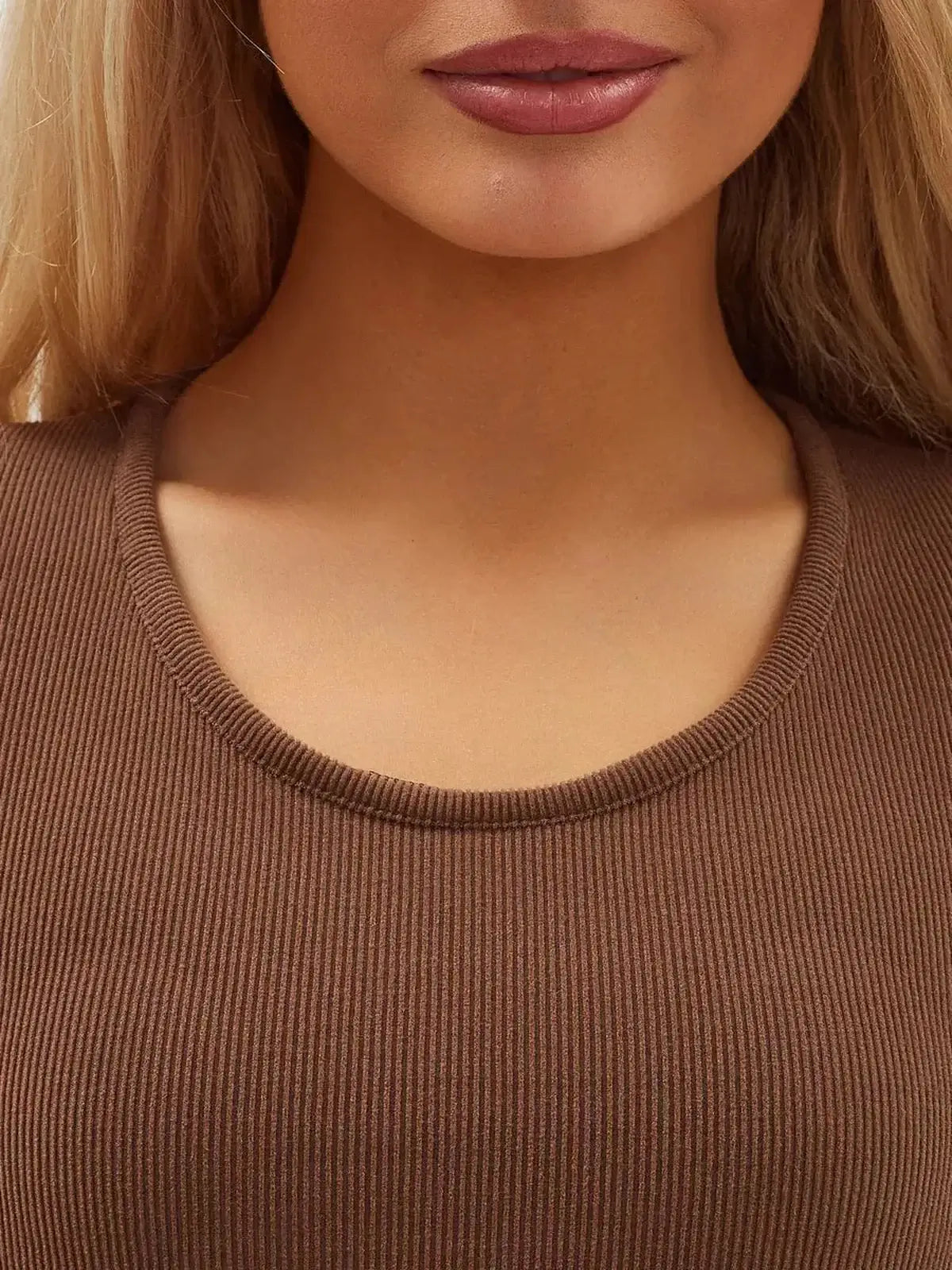 Close-up of a woman wearing a cocoa-colored, ribbed dress neckline showcasing chic, minimalist style.