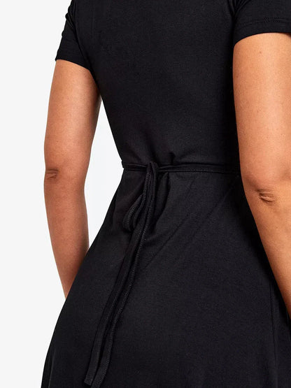 Back view of the black wrap curve mini dress showcasing the tied waist detail and elegant draping.