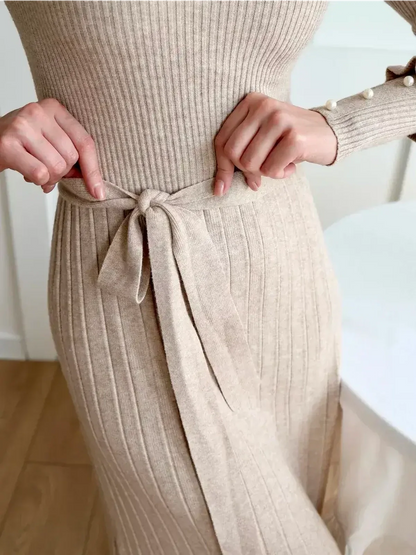 Close-up of the Serene Knit Midi Dress showcasing the ribbed texture and waist tie detail in a light beige color.