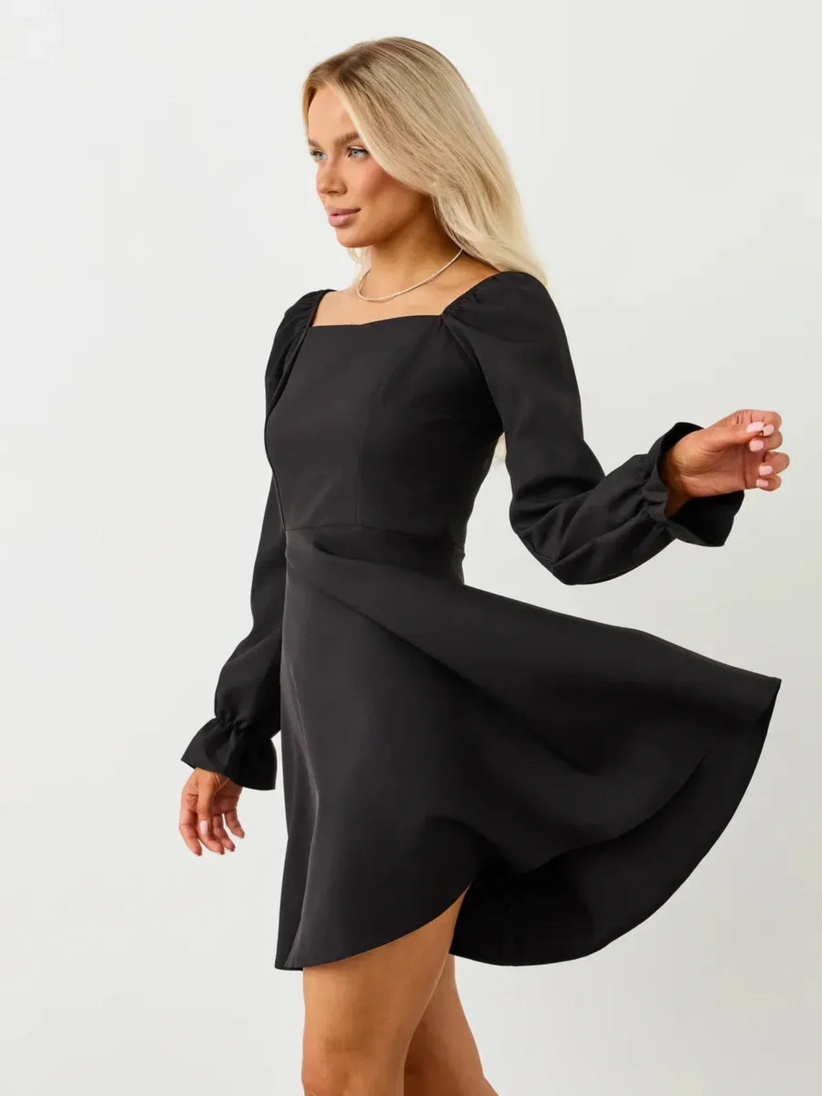 Stylish woman in a black Velvet Hour Mini Dress with voluminous sleeves, perfect for formal events and special occasions.