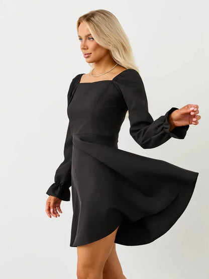 Stylish woman in a black Velvet Hour Mini Dress with voluminous sleeves, perfect for formal events and special occasions.