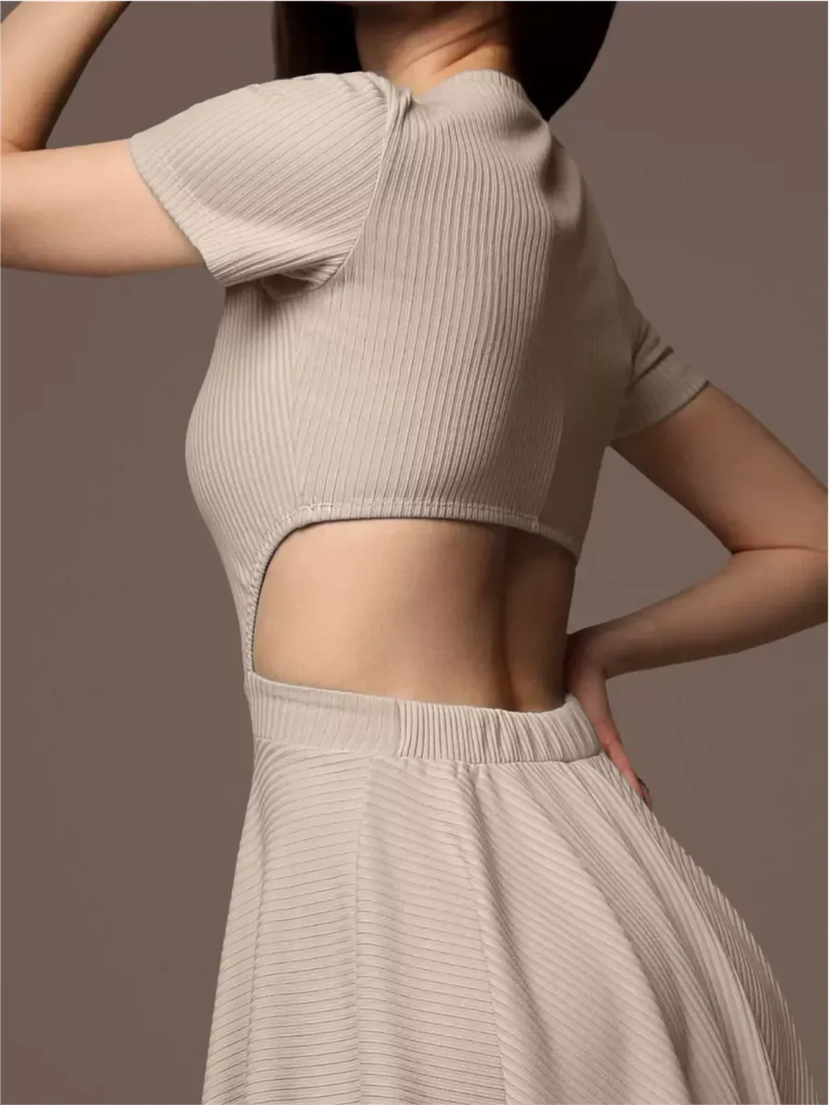 Close-up of a woman modeling a beige Breezy Hour mini dress with a unique open back design and short sleeves.