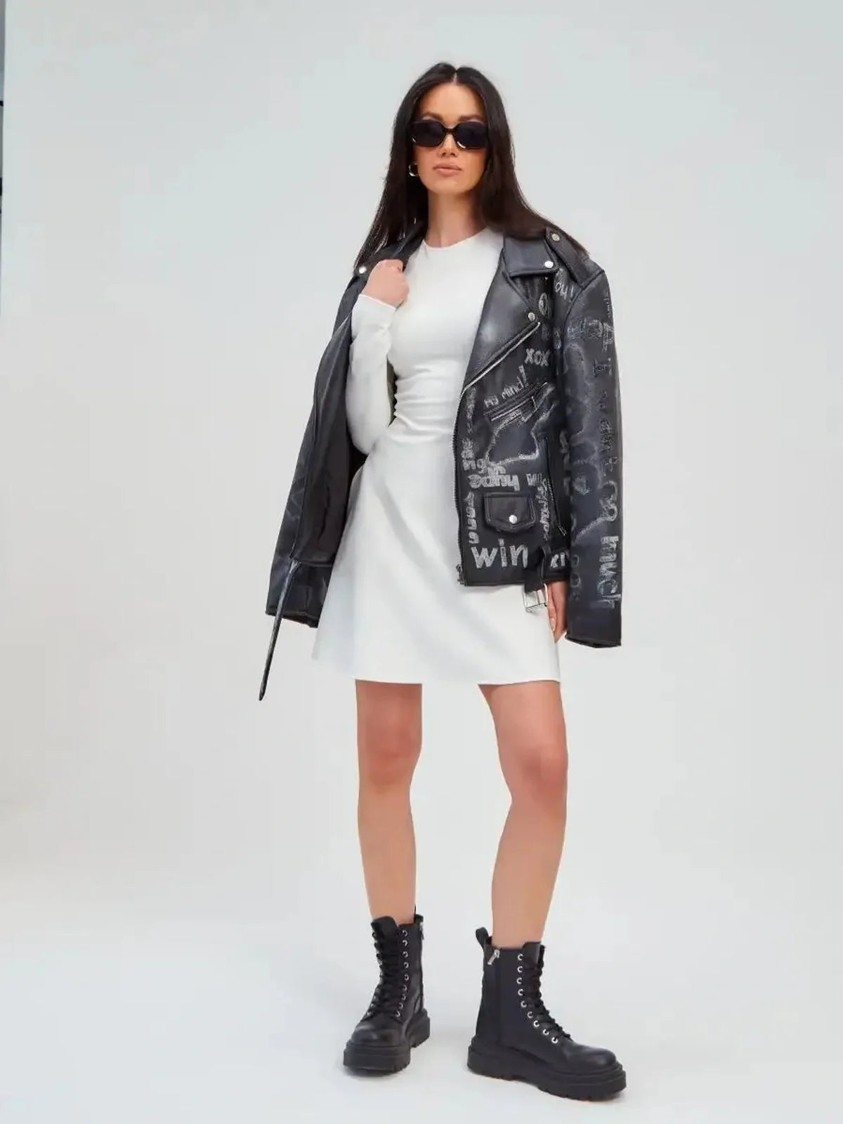 Model wearing an Ivory Sculpt Dress paired with a stylish black leather jacket and chunky boots.