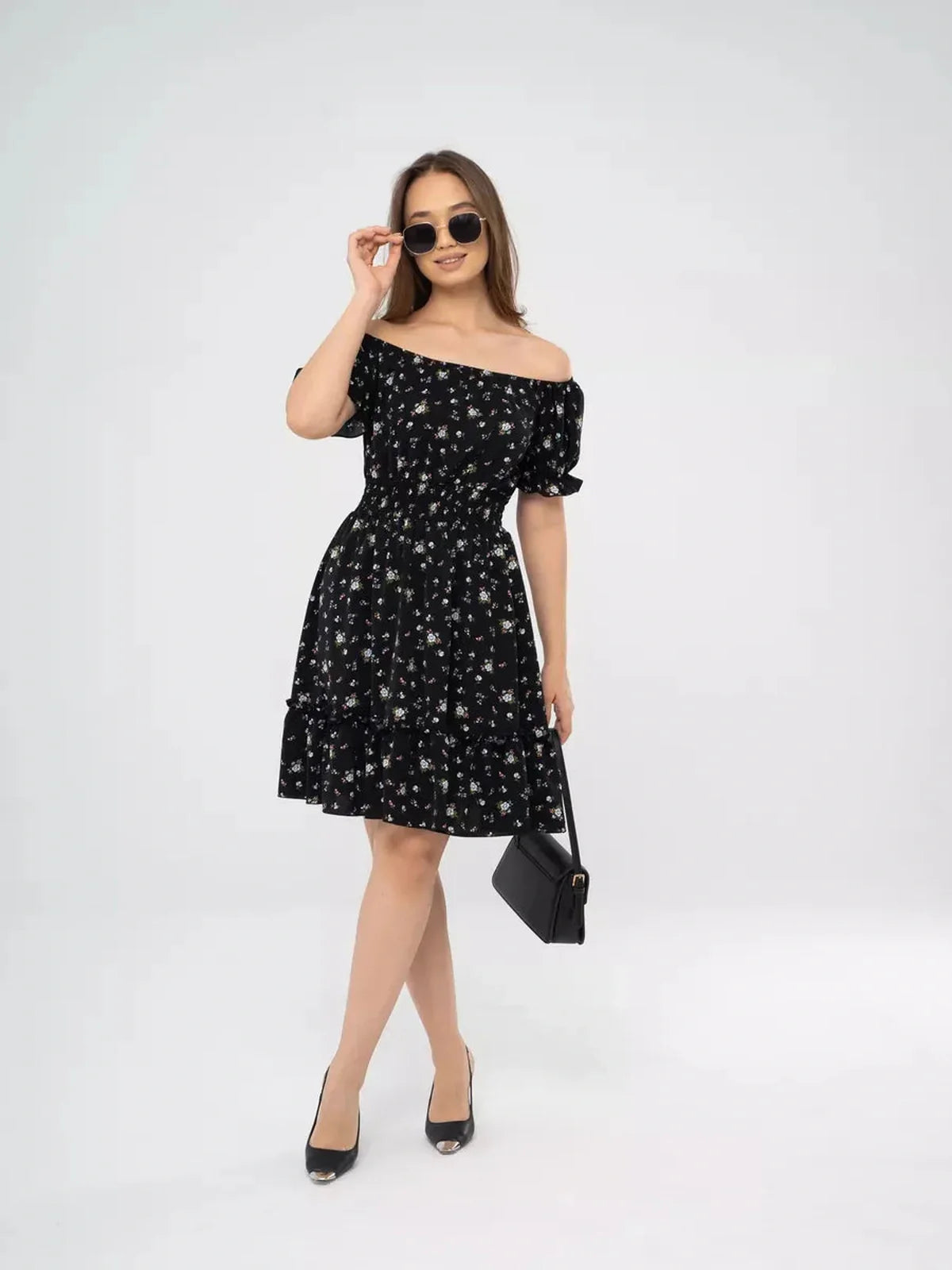 Woman in an off-shoulder black floral dress, perfect for summer events or weddings, stylishly paired with sunglasses.