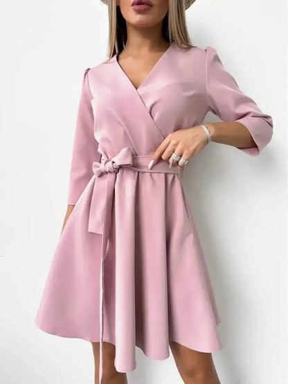 Elegant pink mini dress with V-neckline, long sleeves, and a fitted waistbelt, perfect for weddings or parties.