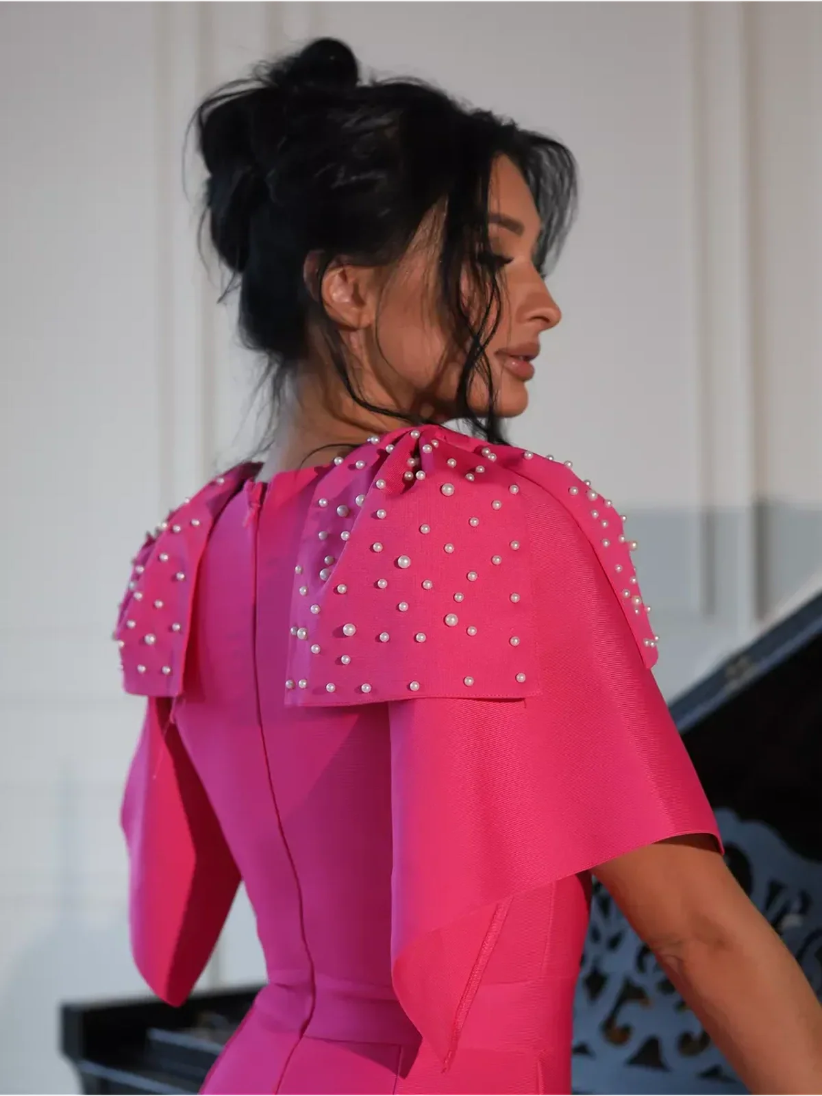 Back view of a woman wearing a fuchsia Pearl Cape Midi Dress with pearl embellishments on the shoulders.