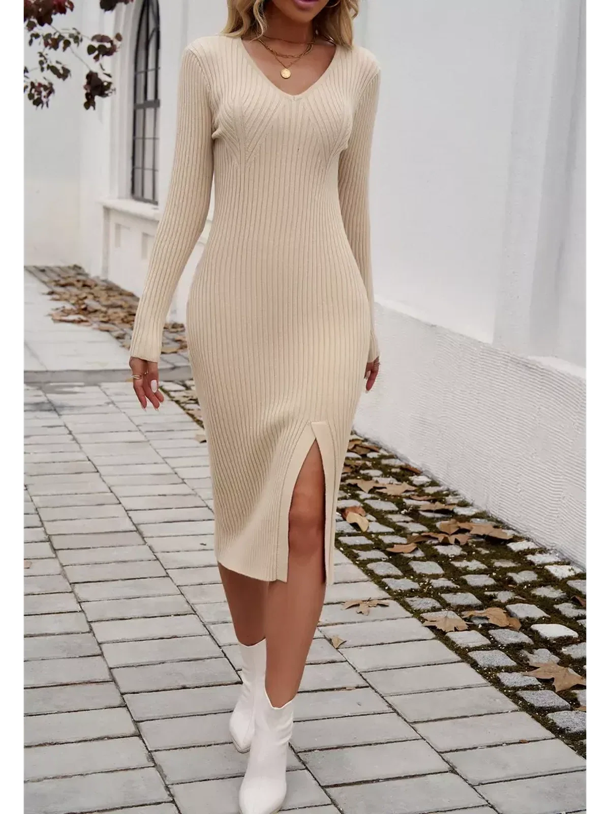 Model wearing a sculpted knit midi dress in light beige with a V-neckline and side slit, perfect for versatile occasions.