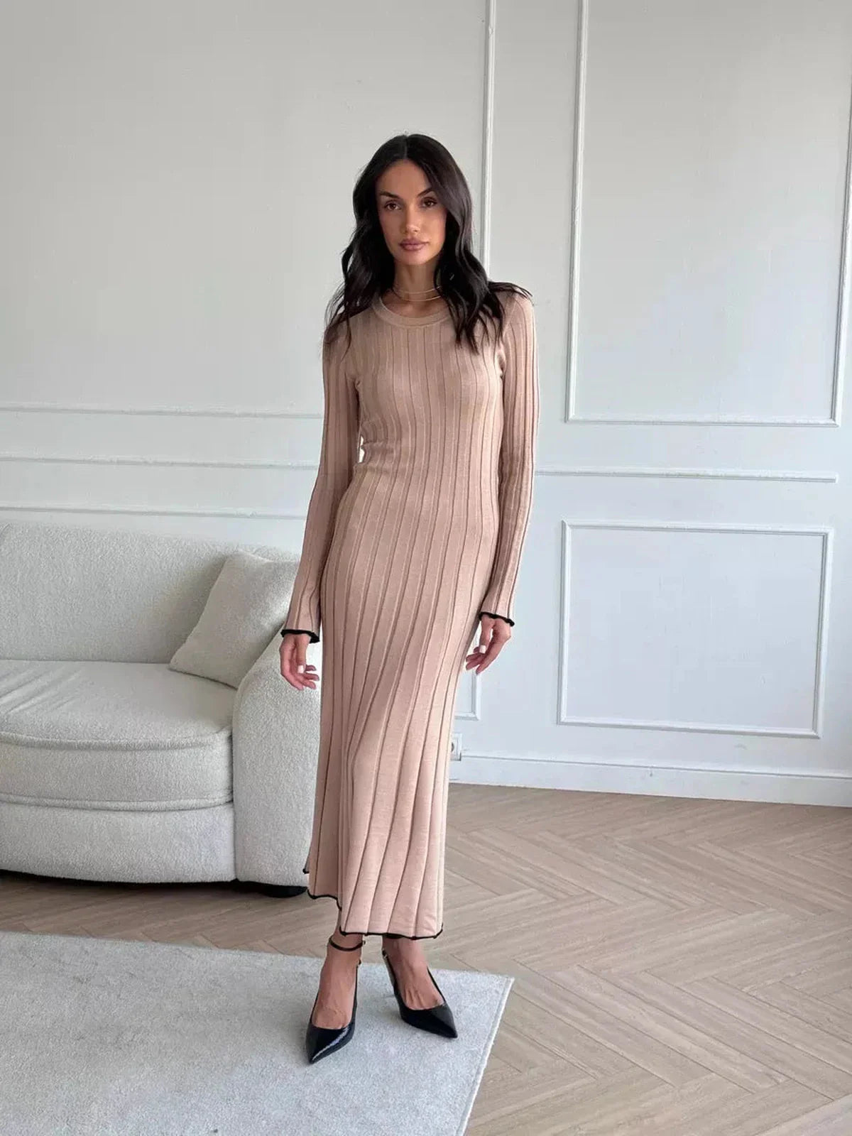 Woman wearing Sahara Curve Maxi Dress in sandstone beige, showcasing its elegant ribbed design and full-length silhouette.