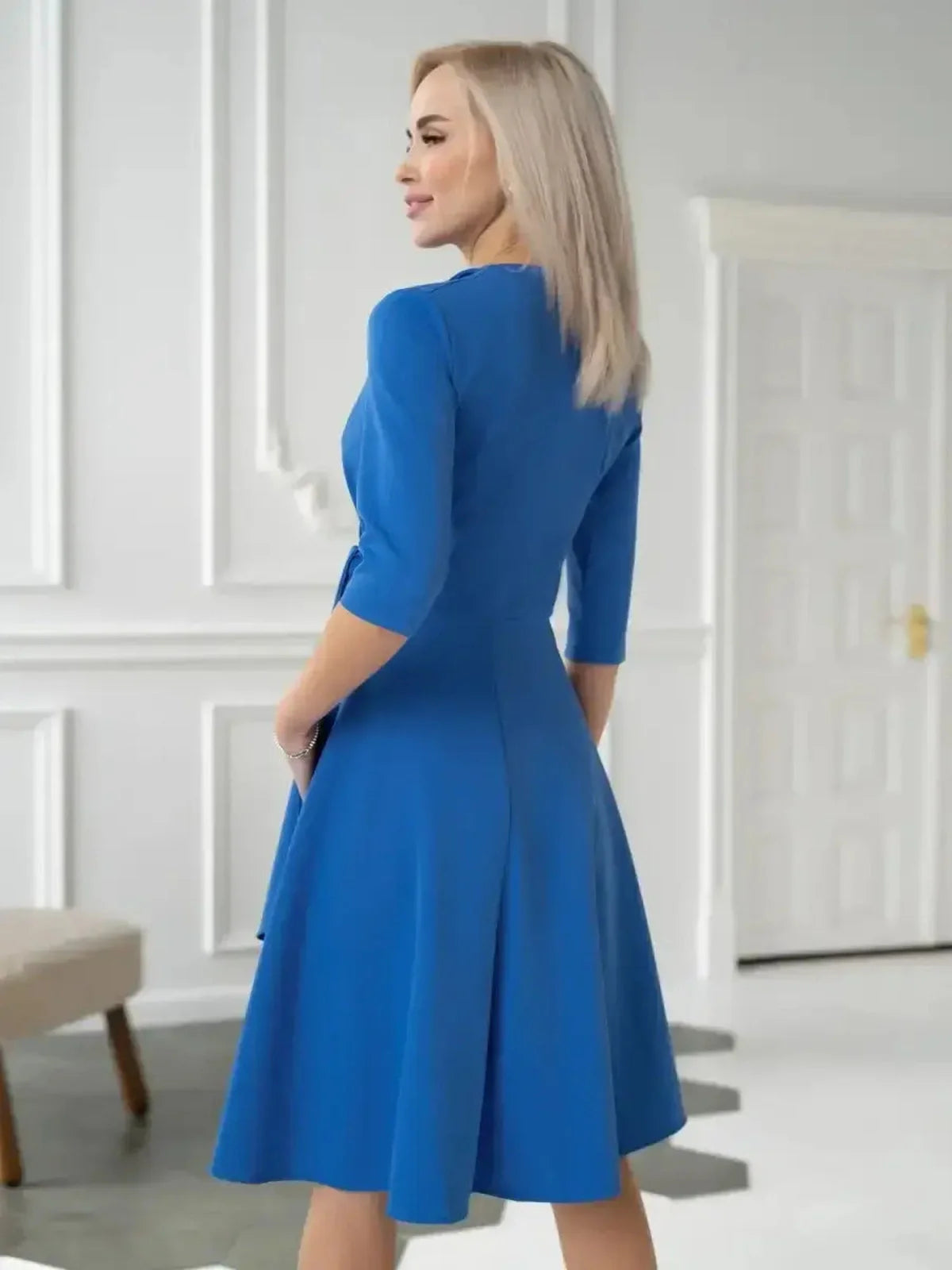 Back view of a woman in a striking royal blue midi dress showcasing draped wrap elegance.