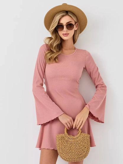 Stylish woman in a pink mini dress with flared sleeves, accessorized with a hat and sunglasses, perfect for summer outings.