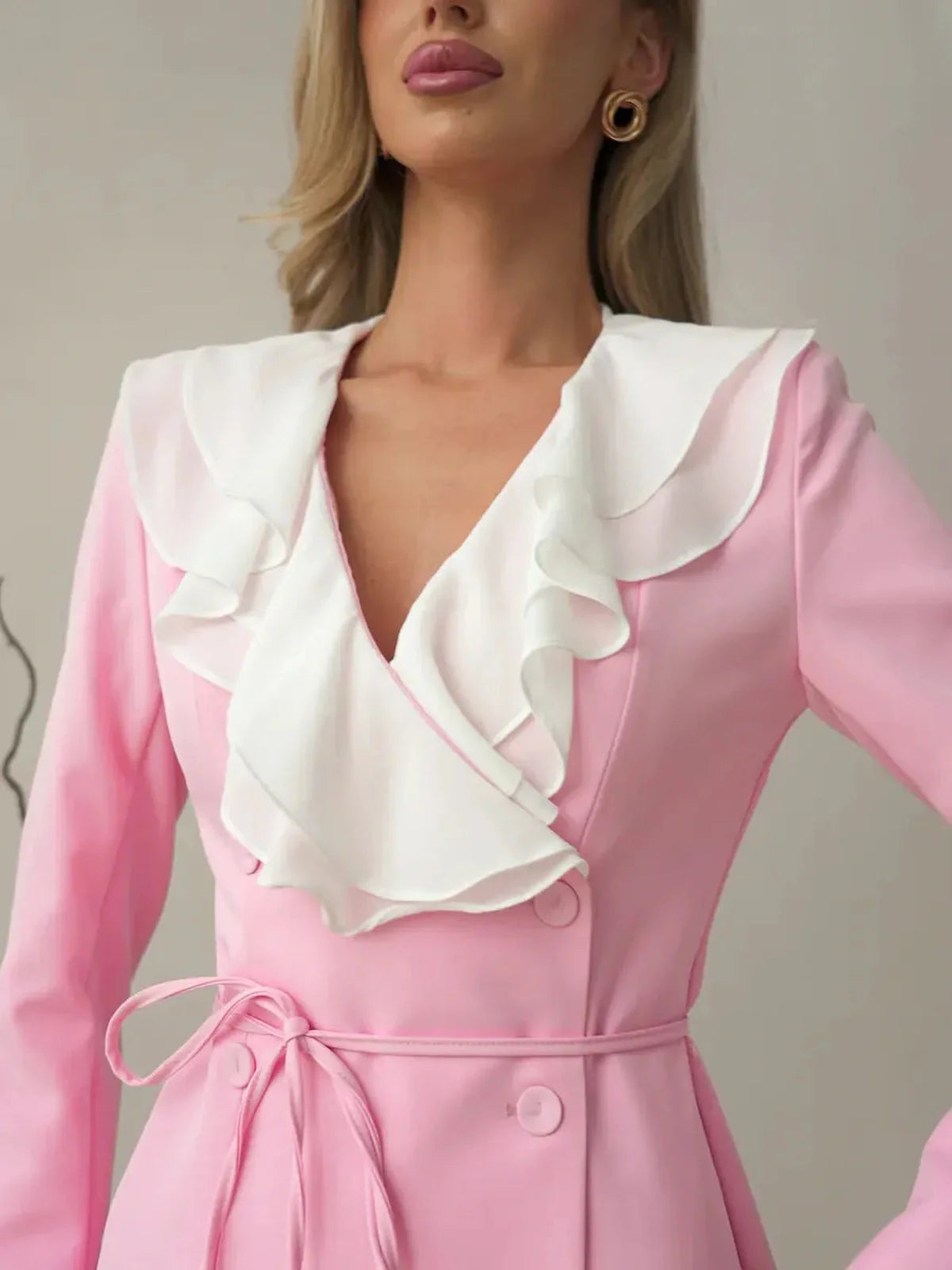 Close-up of a woman in a pink mini dress with a dramatic white ruffle neckline, perfect for summer events.