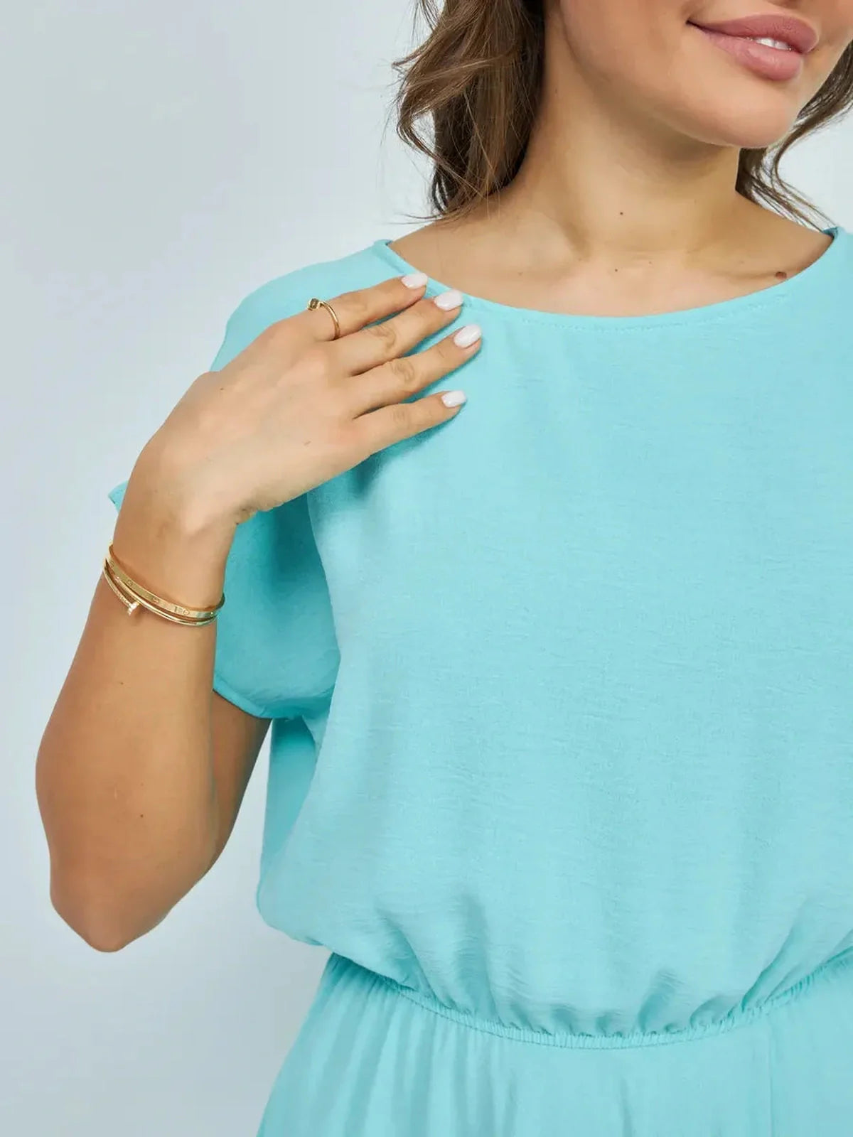Close-up of a woman wearing a light blue maxi dress, showcasing its relaxed neckline and elegant draping.