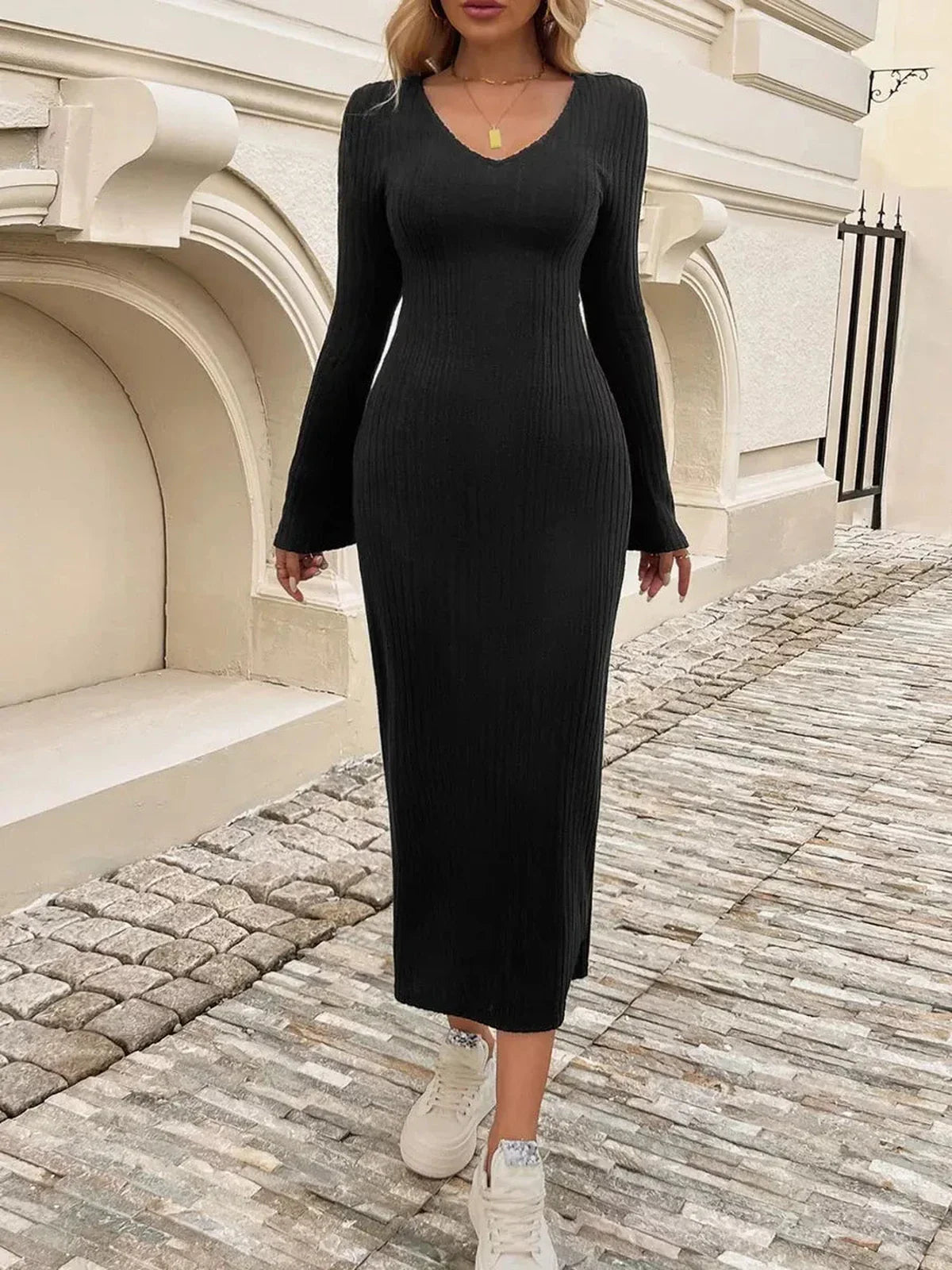 Model wears a Sculpted Chic Midi Dress in black, featuring ribbed knit fabric, bell sleeves, and a flared cuff for elegant style.