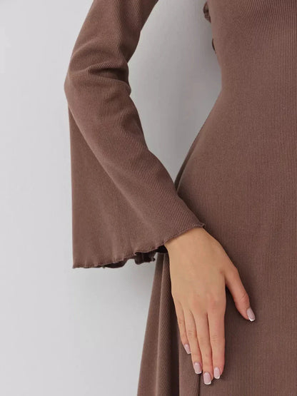 Close-up of a woman's hand on a long sleeve ribbed mini dress with flared cuffs in rich coffee hue.