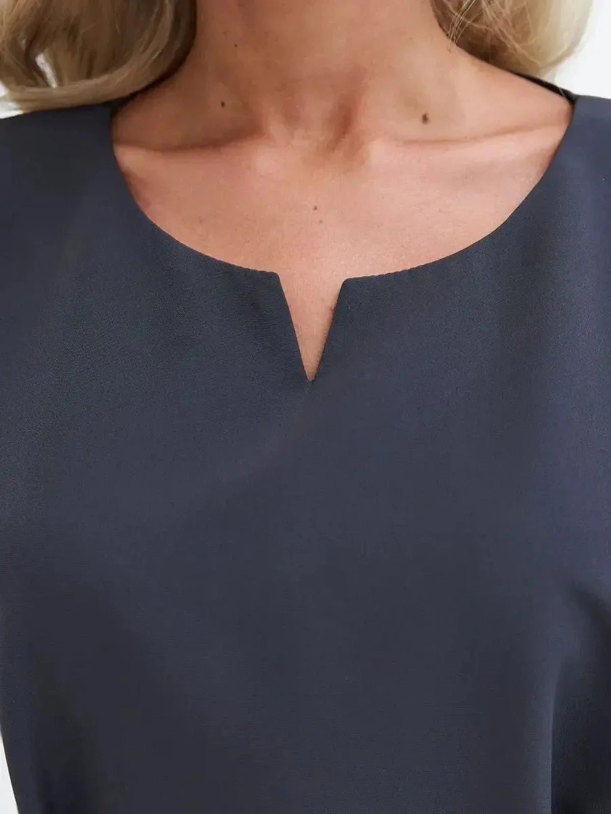 Close-up of the soft round neckline with notch detail of a sophisticated graphite mini dress.