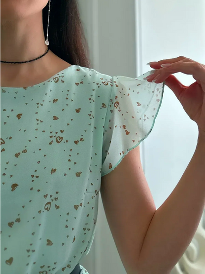 Close-up of a mint chiffon mini dress with fluttery sleeves and a delicate heart print, perfect for summer occasions.