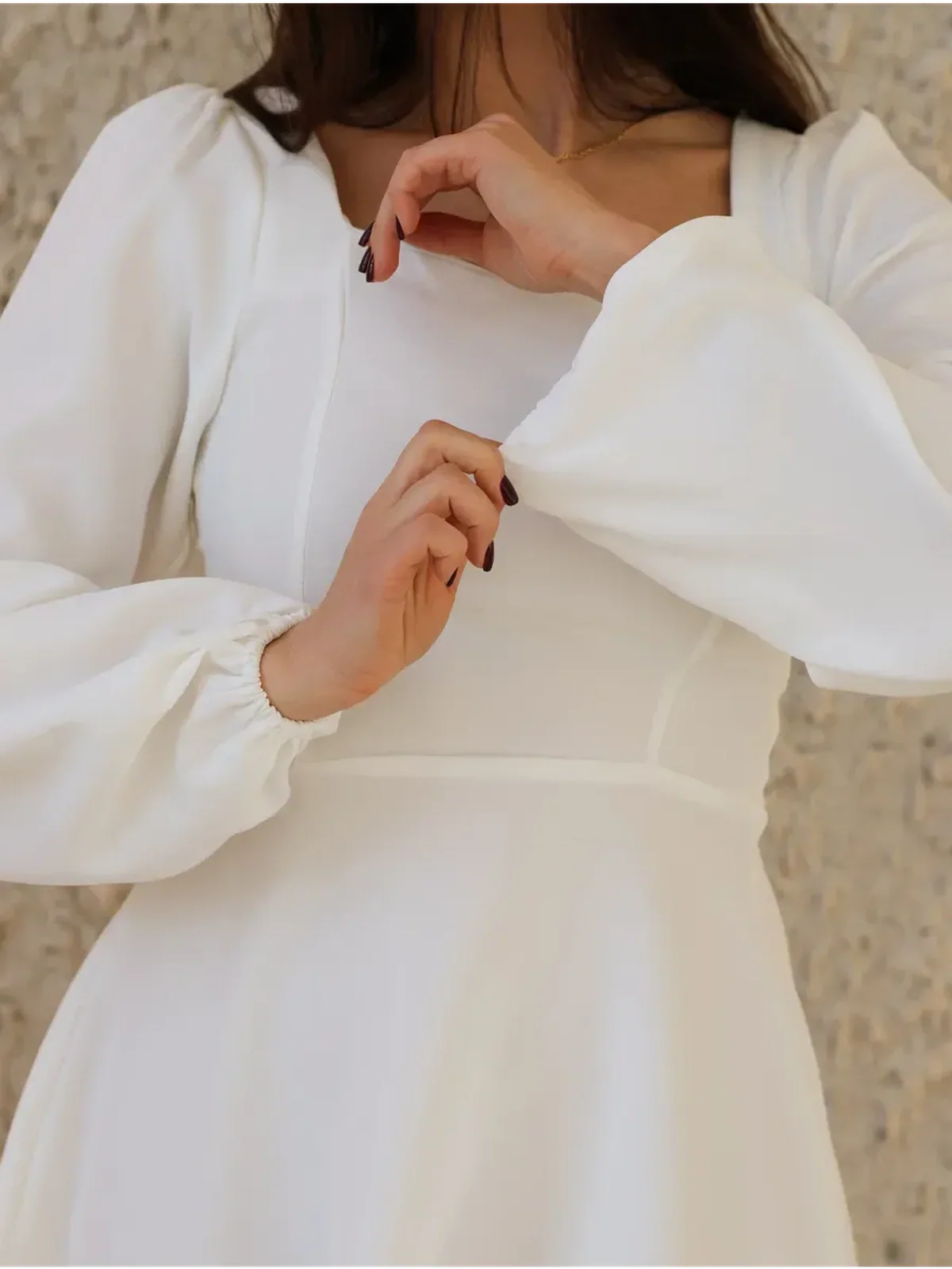 Close-up of a woman wearing an elegant ivory dress with a sweetheart neckline and puff sleeves, ideal for weddings or graduations.