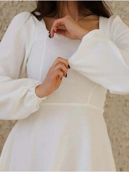 Close-up of a woman wearing an elegant ivory dress with a sweetheart neckline and puff sleeves, ideal for weddings or graduations.