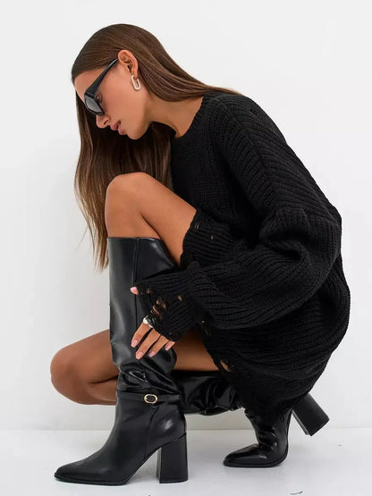 Fashion-forward woman in oversized black knit sweater dress and knee-high black boots, showcasing a chic and casual style.